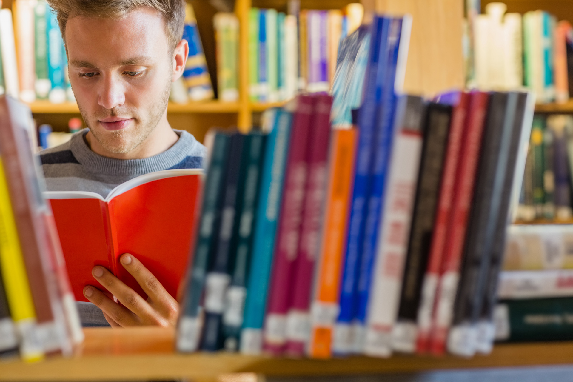 A man is reading in front of some books