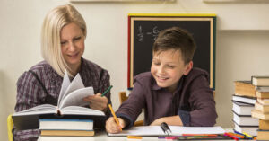 A woman and boy are writing at the desk.